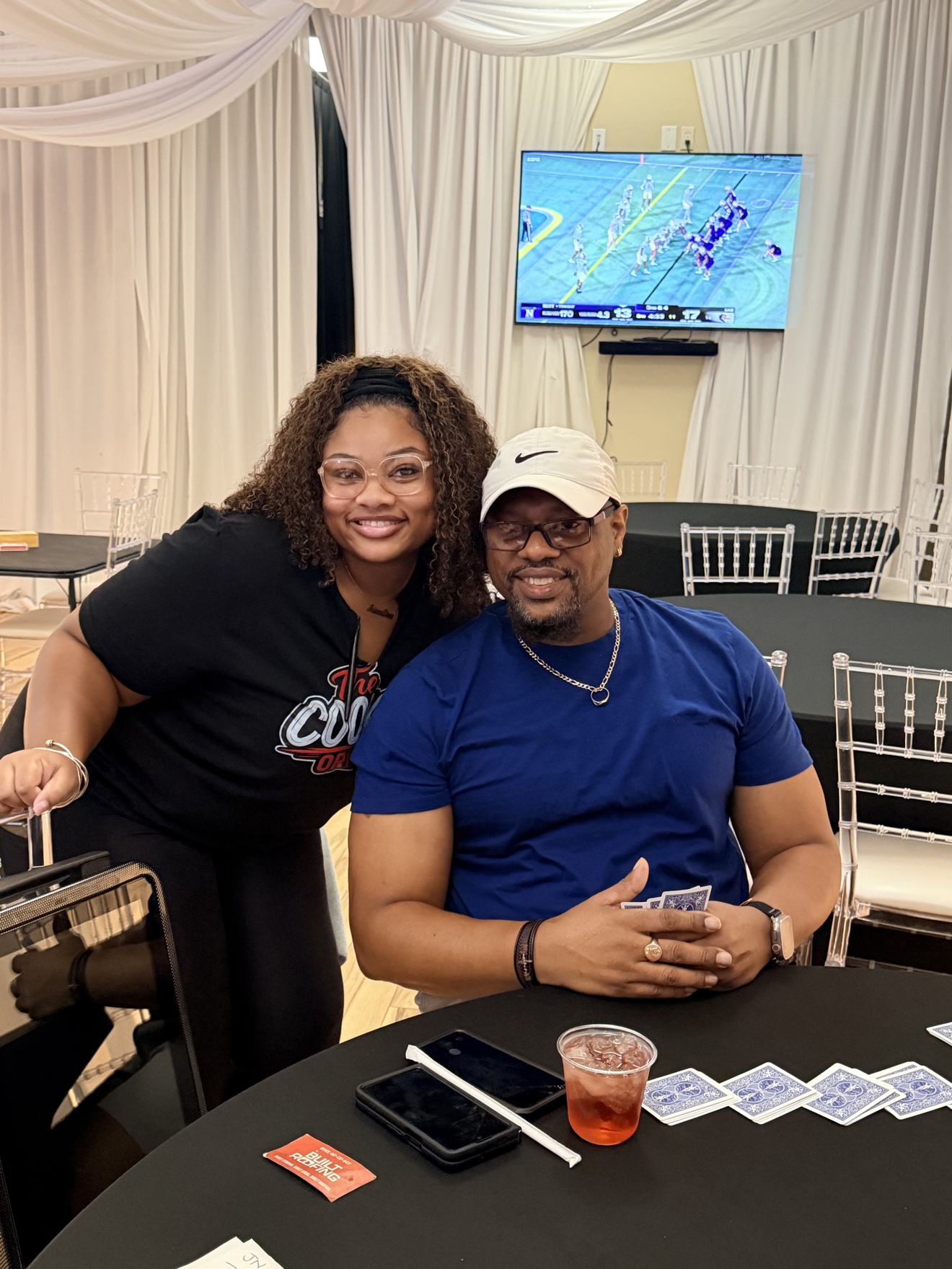 Two Cookout guests smiling together at a card table inside Unique Touch Event Center